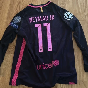 FC Barcelona långärmad Neymar Jr matchtröja - Säljer en långärmad FC Barcelona matchtröja från Nike med Neymar Jr och nummer 11 på ryggen. Tröjan är svart med rosa detaljer, Champions League-patchar på ärmarna och tryck från Qatar Airways och UNICEF. Perfekt för fans av Barca och Neymar. Är i storlek medium