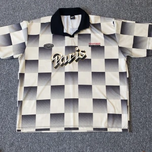 Pull & bear ”Stwd” Paris jersey  - Unik fotbollströja från Swoosh i storlek L med svartvitt rutigt mönster och stor Paris-logga på bröstet. ”Baggy” passform. Tröjan har svart krage, korta ärmar och är tillverkad i ett ventilerande meshmaterial. Snygga detaljer med tryck framtill. Hör av dig vid frågor.