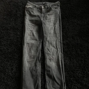 Svarta jeans med råa kanter från ONLY - Säljer ett par svarta jeans från ONLY i storlek 32. Jeansen har raka ben och coola råa, fransiga kanter nertill. Klassisk femficksmodell med knapp och dragkedja. Perfekta för dig som gillar en avslappnad och trendig look.
