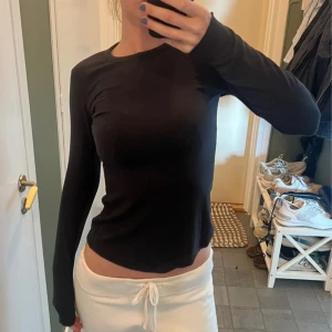 Svart långärmad tröja från Lululemon - Svart långärmad tröja från Lululemon i mjukt och stretchigt material. Slimmad passform som sitter snyggt mot kroppen och rund halsringning. Perfekt till chill eller träning, enkel att matcha med allt.