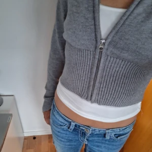 Grå croppad cardigan med dragkedja - Säljer denna koftan från gina tricot, i storlek s / xs. Har aldrig haft på mig den, så helt oanvänd💕 väldigt bra material, tycker inte den sitter så bra på mig💕
