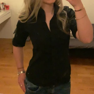 Damskjorta från Tommy Hilfiger - Så snygg svart skjorta från Tommy Hilfiger med långa ärmar, uppvikta på bilden. Bra skick!