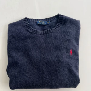 Mörkblå stickad tröja Polo Ralph Lauren - Riktigt snygg mörkblå stickad tröja från Polo Ralph Lauren, passar till allt och i alla tillfällen. Säljer den på grund av att jag tycker den är lite kort i längden. Skick 7/10. Nypris Ca 2000kr