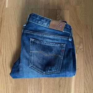 Replay jeans  - Snygga Replay jeans i mörkblå tvätt med klassiska fem fickor och läderpatch med Replay-logga bak. Jeansen har raka ben och subtila slitningar för en cool look. Tillverkade i mjuk bomullsdenim med lite stretch för extra komfort.