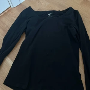 Svart långärmad topp från Lager 157 - En svart långärmad topp från Lager 157 i mjuk bomullsblandning med 5% elastan för extra stretch. Enkel och clean design med rundad halsringning, perfekt att styla med jeans eller kjol. Sitter snyggt och är superbekväm.