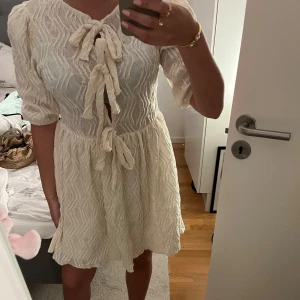 Vit klänning  - Cremevit kort klänning med knyten ovanför bröstet. Aldrig andvänt, prislappen kvar!