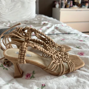 Beige sandaler med knyt och klack från Nelly - Snygga beige sandaler med medelklack från Nelly med flätade remmar och knyt runt vristen. Helt oanvända 💞storlek 38 (normal i storleken)