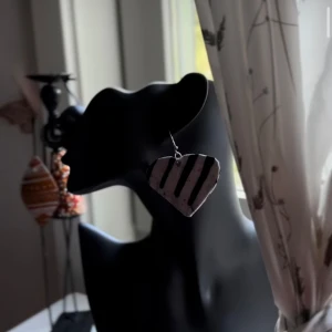 Randigt hjärtformat örhänge - Coolt örhänge i hjärtform med svartvita ränder. Statement piece som verkligen sticker ut och ger en edgy vibe till din look. Perfekt för dig som gillar unika accessoarer och vill ha något som syns. Följ oss för mer på Instagram; @shop_with_tyra