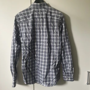 Rutig slim fit skjorta Selected Homme - Snygg rutig skjorta från Selected Homme i slim fit-modell. Skjortan har klassisk krage, knäppning framtill och långa ärmar. Färgkombination i blått, vitt och grått. Perfekt för dig som gillar stilrena och moderna plagg. Varan är helt ny och har aldrig använts