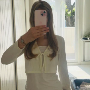 Vit croppad kofta med knyt från Hm  - Superfin vit croppad kofta från Hm med ribbad struktur och knyt framtill. Långärmad och i mjuk bomullsmix, perfekt att slänga över ett linne eller topp. Enkel och stilren design som passar till allt.