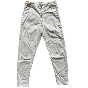 Beiga chinos från Gant - Snygga beiga chinos från Gant med klassisk passform och raka ben. Byxorna har fickor fram och bak, samt stängs med knapp och dragkedja. Perfekta för en clean och stilren look. Materialet är mjukt och skönt i bomull.