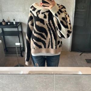 Beige och svart stickad zebramönstrad tröja - Säljer en oversized stickad tröja med zebramönster i beige, svart och vitt. Sjukt mysig tröja☺️