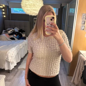 Beige strukturerad topp från Lindex - Superfin beige topp från Lindex med kort ärm och coolt strukturerat tyg. Toppen är endast använd ett fåtal gånger och i mycket bra skick🤍