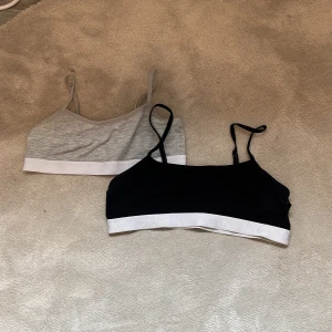 2-pack trikåttopp från H&M - Två stycken trikåttopp från H&M, en i svart och en i ljusgrått. Båda har smala axelband och vit resårkant nedtill med logga nertill. Hör av er vid frågor eller intresse❤️