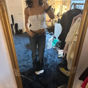 Vit broderad croppad linnetopp från Zara - Säljer en söt vit croppad linnetopp från Zara med broderade detaljer och smala axelband. Toppen har en romantisk känsla med spets och knytning framtill. Perfekt för varma dagar eller lager på lager. Står M men sitter som XS/S