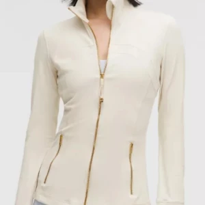 Vit zip-jacka med guldiga detaljer - Snygg vit jacka med guldiga dragkedjor och hög krage. Figurnära passform och långa ärmar med tumhål. Perfekt för en sportig och stilren look. Säljer då jag har 2 av samma fick denna 2 dagar sedan helt ny 💕 