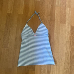 Blå- och vitrandig halterneck-linnetopp - Säljer en söt blå- och vitrandig halterneck-linnetopp med v-ringning och knyt i nacken.Har sytt själv. Perfekt för varma dagar och enkel att matcha med jeans eller kjol.