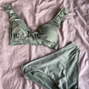 Grön bikini med volang från Kappahl - Ljusgrön bikini från Kappahl i storlek XS. Överdelen har volangdetaljer längs axelbanden och en mjuk, bekväm passform.