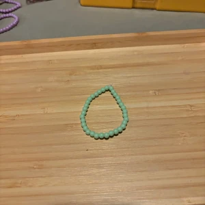 Mintgrönt pärlarmband - Säljer ett stretchigt armband med små mintgröna pärlor. Perfekt att matcha med andra smycken för en färgglad look.