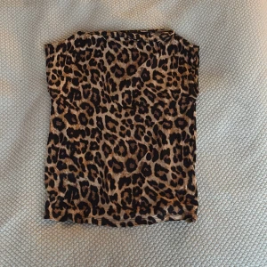 Leopardmönstrad topp från The Black Label Collection - Säljer en snygg leopardmönstrad topp från The Black Label Collection i storlek S. Toppen har en tight passform och är ärmlös, perfekt för att sticka ut med ett djurmönster. Materialet är mjukt och stretchigt för en bekväm känsla.