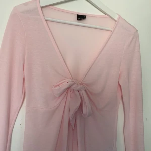 Ljusrosa långärmad topp med knyt - Söt ljusrosa långärmad topp från Gina Tricot med djup v-ringning och knyt framtill. Tunn och mjuk i materialet, perfekt för lager-på-lager eller som den är.💗