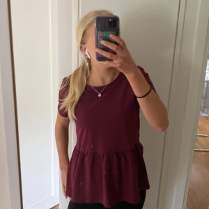Vinröd topp med volang - Säljer en vinröd topp med rund halsringning och volang nedtill från Lindex. Storlek 170 men passar både xs och s! Aldrig använd 💓