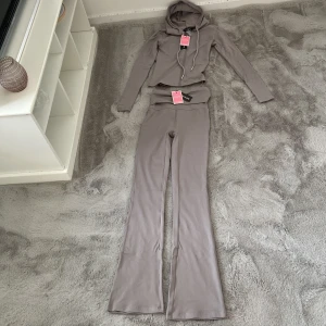 Beige hoodie med matchande byxor från PrettyLittleThing - Säljer denna superstretchiga och bekväma yoga-dress från PrettyLittleThing i en stilren ljusgrå färg. Köpte den tillsammans med en annan i fel storlek, så denna är också helt oanvänd – inte testad!  ✅ Storlek: XXS ✅ Färg: Ljusgrå ✅ Material: Stretchigt och följsamt – perfekt för yoga, träning eller hemmamys ✅ Skick: Ny, aldrig använd  Supersnygg och skön set för dig som gillar att kombinera stil och komfort 💫  💌 Hör av dig om du vill se fler bilder eller om du är intresserad!