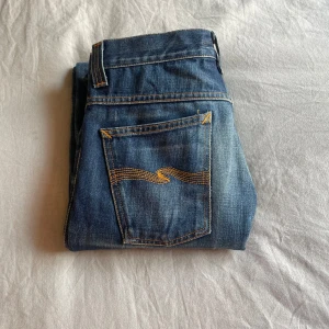 Blå bootcut jeans från Nudie Jeans - Säljer ett par klassiska blå bootcut jeans från märker Nudie Jeans i modellen ”Bootcut Ola” med snygg jeansfärg, mycket stretch och i väldigt bra skick. Nypris är 2500 kr men säljer för 1 000 kr! Jag säljer då dem tyvärr är för stora för mig. Jag har vanligtvis storlek XS/S och skulle uppskatta dessa till storlek M.  Innerbenslängden är 86 cm och midjemåttet tvärsöver är 37 cm! ❤️