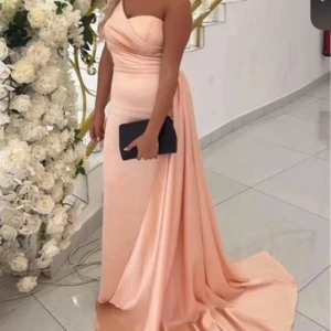 Champagnefärgad långklänning med drapering - Säljer en elegant långklänning i champagnefärg med draperad överdel och axelbandslös design. Klänningen har en vacker släp och figurnära passform som ger en lyxig känsla. Perfekt för bal eller fest! 💫