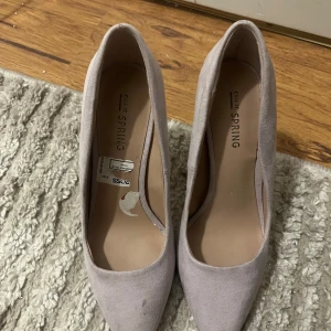 Ljuslila pumps från Call It Spring - Säljer ett par stilrena pumps i ljuslila mocka från Call It Spring. Skorna har spetsig tå och smal klack, perfekta för att lyfta din outfit. Klassisk design med elegant form och mjukt material.