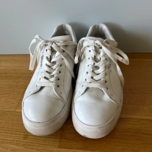 Vita läder sneakers från Tamaris - Klassiska vita sneakers från Tamaris med rund tå och snörning. Skorna har en platt sula och är tillverkade i läder. Gott skick och normal i storleken!