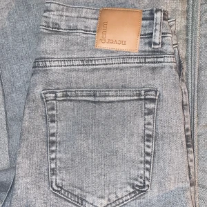 Grå jeansbyxor från Never Denim - Snygga grå jeansbyxor från Never Denim med klassisk femficksdesign och en ljus tvätt. Byxorna har en rak passform och normal midja, perfekta till vardagslooken. Stilsäkra och lätta att matcha med det mesta. Jeansen är från Bik bok. Stora i storleken. 