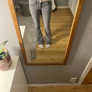 Grå low waist bootcut jeans - Säljer ett par gråa bootcut jeans med klassisk femficksdesign och normal passform. Jeansen har låg midja och är tillverkade i ett mjukt denimtyg. 