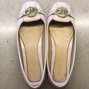 Beige ballerinaskor från Michael Kors - Snygga beige ballerinaskor från Michael Kors. Skorna har rund tå och platt sula, perfekt för en stilren och klassisk look. Tillverkade i skinn med fina detaljer och diskret sömnad. Jättefina för skolavslutning elr fest mm, perfekt för att lyxa till outfiten lite. Såklart är skorna äkta!!!! Köpta här på Plick för 500! Har används fåtal gånger efter det!! På kartongen står det att storleken är 40 men själv är jag en 39 och passar utmärkt!! Putsar till skorna innan de skickas!🥰 kan gå ned i pris 
