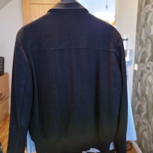 Svart skepparkavaj - Snygg svart skepparkavaj med dubbelknäppning och stilrena detaljer. Jackan har långa ärmar och en klassisk krage. Perfekt för en stilren look.