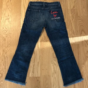 Moschino Jeans  - Jeans från Moschino. Low-waist och croppad modell med rå kant. Innerbenslängd är ca 53 cm. 