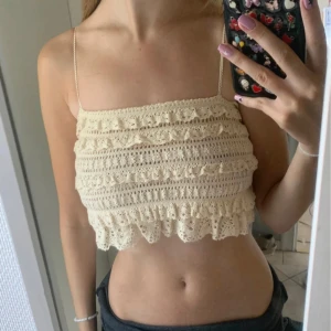 Beige spetslinne ZARA - Säljer ett sött beige spetslinne med smala axelband. Toppen är croppad och har volangdetaljer som ger en romantisk känsla. Perfekt för varma sommardagar!