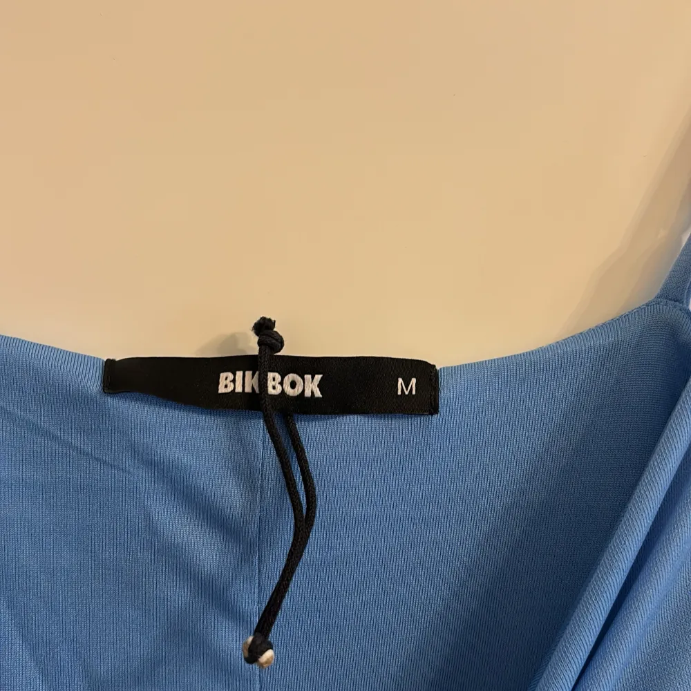 Säljer en stilren blå långklänning från Bik Bok. Klänningen har smala axelband och en enkel design som gör den perfekt för olika tillfällen. Materialet känns mjukt och bekvämt mot huden. Perfekt för dig som vill ha en elegant och minimalistisk look.. Mekot.