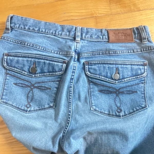 Blå jeans från Lauren Jeans Co. - Snygga blå jeans från Lauren Jeans Co. med broderade detaljer på bakfickorna. De har en klassisk femficksdesign och en bekväm passform. Perfekta för en avslappnad stil. Tror de är mid waist! Säljer då de är för stora på mig💓 ralph lauren