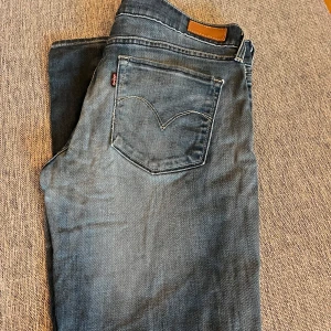 Blå jeans från Levi's - Snygga blå jeans från Levi's med klassisk femficksdesign och knappgylf. Perfekta för en avslappnad stil. Levi's-logga på bakfickan ger en ikonisk touch.