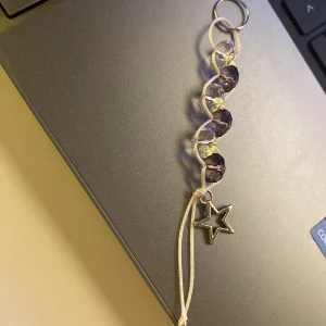 Nyckelring med stjärnhänge och pärlor - Snygg nyckelring med lila och klara pärlor i en tvinnad design. Nyckelringen har ett silverfärgat stjärnhänge. Perfekt för att lägga till en touch av elegans. Hemmagjord nyckelring eller telefon smycke