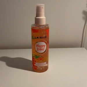 Happy Vibes Body & Hair Mist från La Rive - Fräsch och upplyftande body & hair mist från La Rive med namnet Happy Vibes. Flaskan är genomskinlig med en färgglad etikett i orange och rosa toner. Innehåller vitamin E och provitaminer B5 för extra vård.