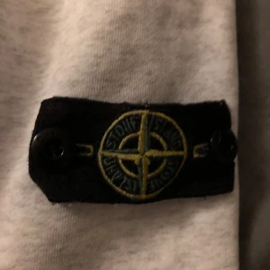 Vit tröja från Stone Island - Säljer en stilren vit tröja från Stone Island med deras ikoniska märke på ärmen. Tröjan har långa ärmar och en rund halsringning. Perfekt för en avslappnad och trendig look. 