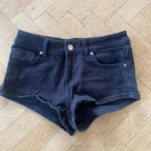Svarta jeansshorts från H&M Divided - Snygga svarta jeansshorts från H&M Divided. De har en lågmidjad design med klassiska femficksdetaljer och knappgylf. Ungefär 2 år gamla inte andvända så många gånger och är i storlek 34.