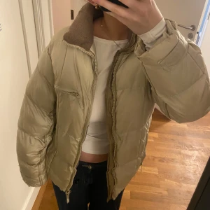Beige pufferjacka - Säljer en snygg beige pufferjacka med dragkedja och hög krage. 