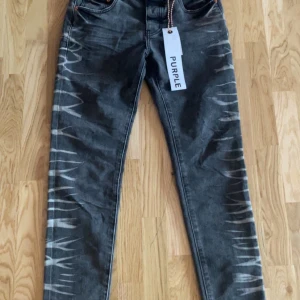 Grå jeans med mönster från Purple - Snygga grå jeans från Purple med unikt mönster längs benen. De har en klassisk femficksdesign och knappgylf. Perfekta för dig som vill sticka ut med en cool stil.