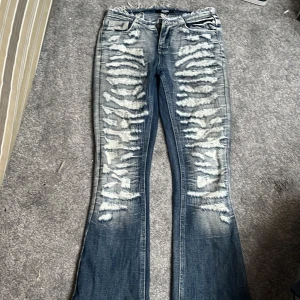 Blå bootcut jeans från Jaded London - Snygga blå bootcut jeans från Jaded London med slitna detaljer och en cool tvättad look. Jeansen har en låg midja och är perfekta för en avslappnad stil. De har klassiska fem fickor och en dragkedja framtill. Tyvärr är de lite trasiga nertill därav det billigare priset. Men det är lätt att sy igen eller klippa bort. Detta eftersom att byxorna är lite för långa för mig och därmed trampar jag tyvärr sönder dem❤️