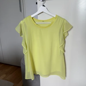 Gul blus med volangärmar - •Säljer en ljusgul blus med volangärmar.  •Blusen har en luftig design med dubbla lager tyg(har ett foder) och rund halsringning.  •Perfekt för en somrig look. •Storlek S. Etiketten är bortklippt. •Sparsamt använd, ingenting att anmärka på. Nyskick. Tvättad. •Djur & rökfritt hem.