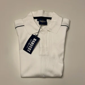 Vit pikétröja från Harvest - Säljer en helt ny och oanvänd vit pikétröja från Harvest. Tröjan har en klassisk krage och korta ärmar med diskreta mörka detaljer vid axlarna. Perfekt för en sportig och avslappnad look. Passar bra till både jeans och shorts. Nypris på en James harvest piqe ligger runt 500kr. Denna säljs endast för 199!