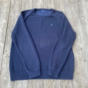 Mörkblå stickad tröja från Polo Ralph Lauren - Säljer en stilren mörkblå stickad tröja från Polo Ralph Lauren. Tröjan har långa ärmar och ett diskret broderat märke på bröstet. Perfekt för en klassisk och avslappnad look.